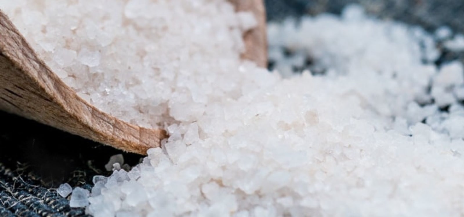 Crystals of Sacred Valley Salt spilling out of a wooden scoop