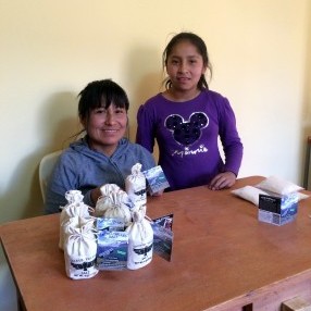 Nilda, together with her daughter Fiorela, smiling with pouches of Sacred Valley Salt that she has prepared