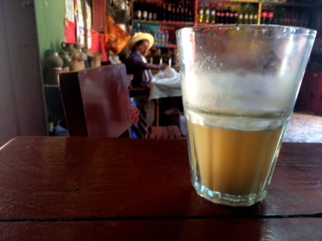 Looking over a large glass of chicha at the dusty interior of a chicharia in Urubamba, Peru