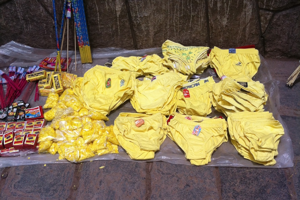 Different styles and sizes of bright yellow underwear displayed for sale on the sidewalk