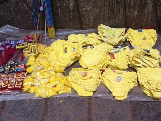 Different styles and sizes of bright yellow underwear displayed for sale on the sidewalk