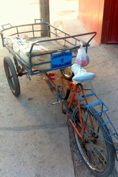 A three wheeled device in which the two front wheels carry a platform for hauling goods while the rider sits above the third wheel in the rear