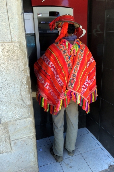 Man in traditional brightly colored hand woven pancho standing at an ATM