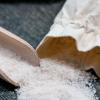 Small grain salt poured from pouch with wooden scoop